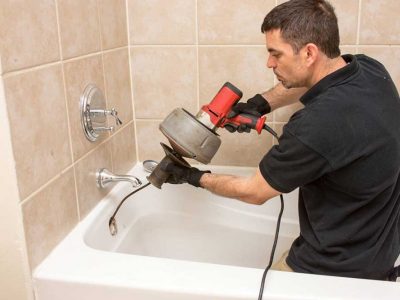 plumber unclogging bathtub